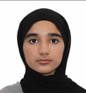 Grade 9 student wearing a light grey hijab and a black top, standing upright and facing the camera. Photo centred on a blue graphic background.
