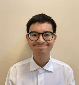 Grade 10 student with short dark hair, wearing glasses and a blue t-shirt, upright and facing the camera. Photo centred on a blue graphic background.