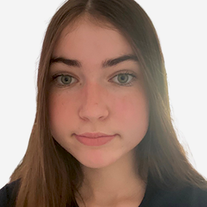 Élève aux longs cheveux bruns et aux yeux verts portant un haut noir, souriant légèrement devant un fond blanc.